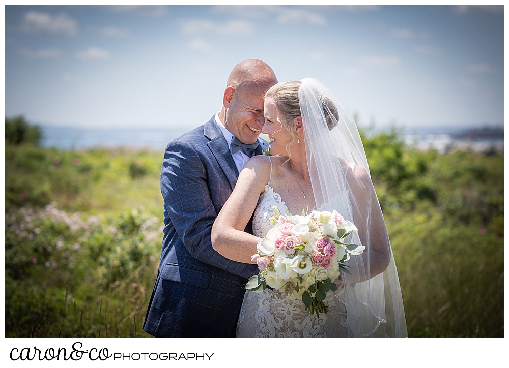 a groom stands behind his bride, her head is turned towards him and their foreheads are touching