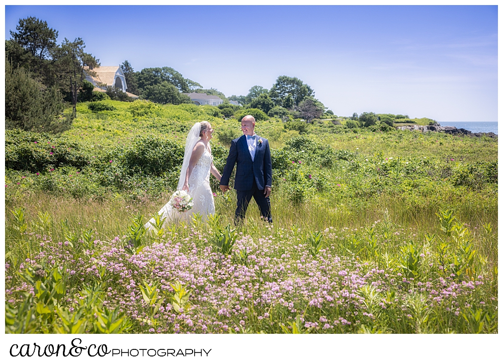 a bride and groom walk among the beach roses in Kennebunkport maine