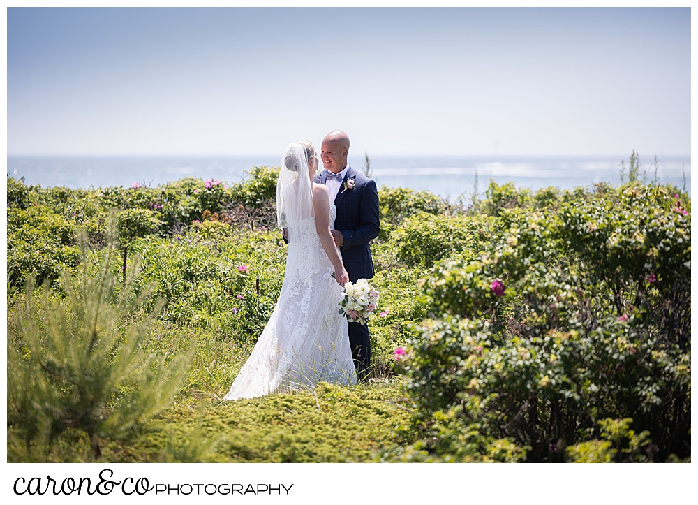 a bride and groom stand together among the Beach roses in Kennebunkport Maine