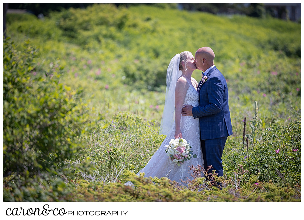 a bride and groom kiss among the beach roses in Kennebunkport maine
