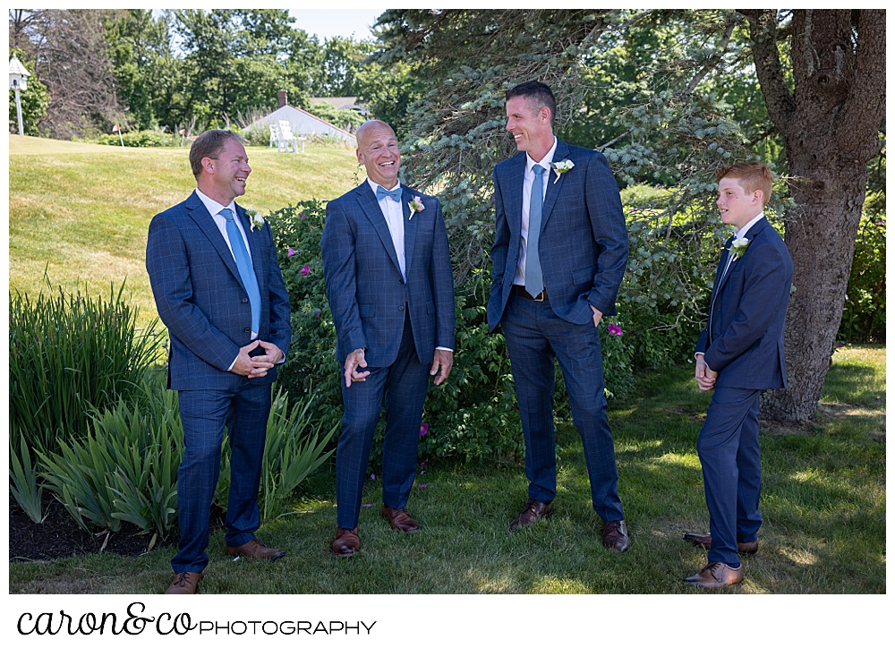 a groom stands with his groomsmen as they laugh and talk