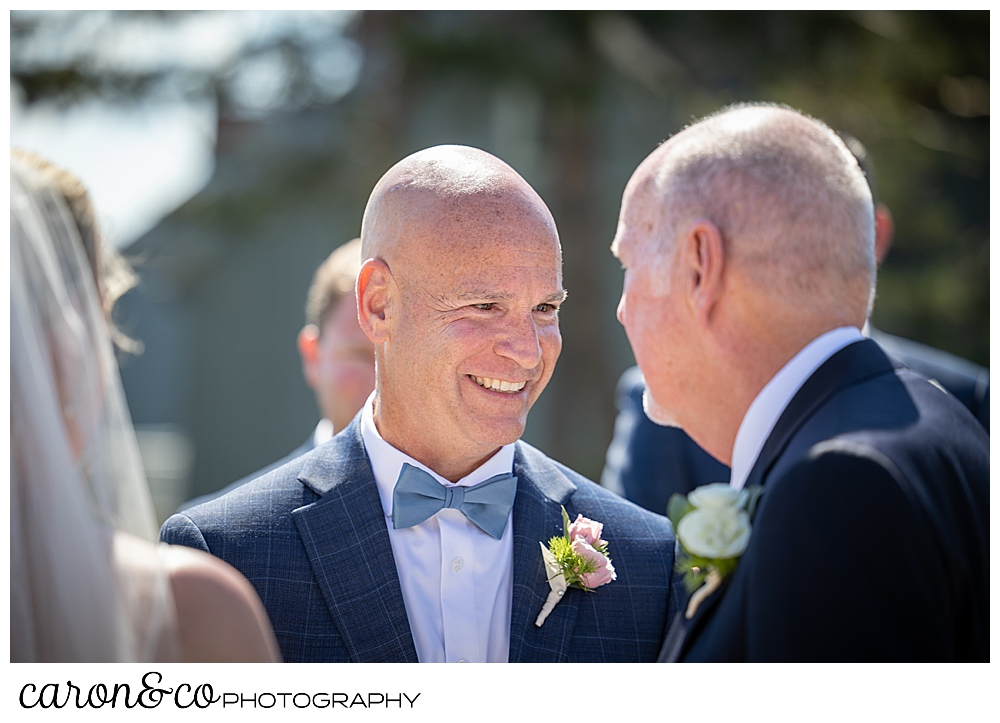 a groom smiles as he looks at the bride's father during a Kennebunkport Maine colony hotel wedding ceremony