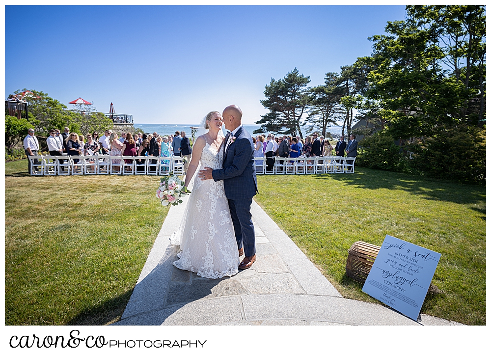 a bride and groom embrace during their recessional at a Kennebunkport Maine colony hotel wedding ceremony