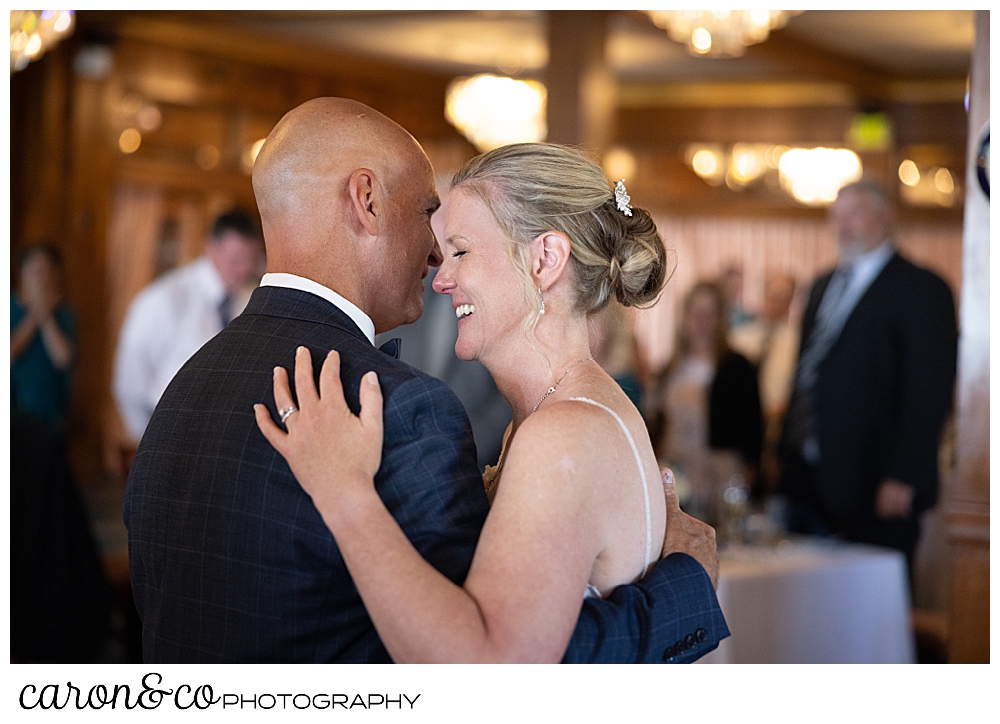 a bride and groom are smiling as they dance their first dance at a colony hotel Kennebunkport wedding reception