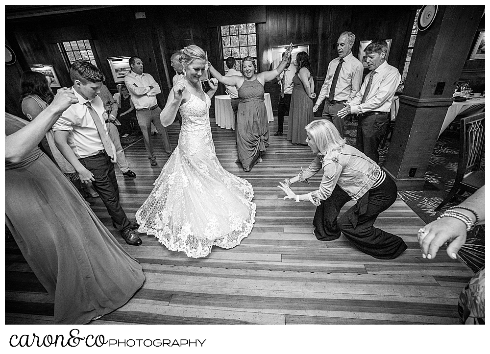 black and white photo of a bride twirling on the dance floor as a guest bends down toward the hem of the bride's dress during a colony hotel Kennebunkport Maine wedding reception
