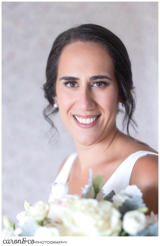 a beautiful bridal portrait of a smiling bride, holding a bridal bouquet of white and green