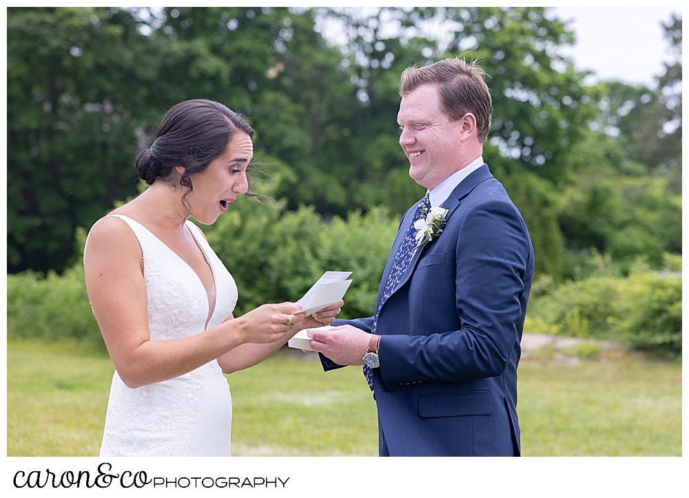 a bride reads a note from her groom as he looks on during their wedding day first look at their Kennebunkport Maine wedding at the colony hotel