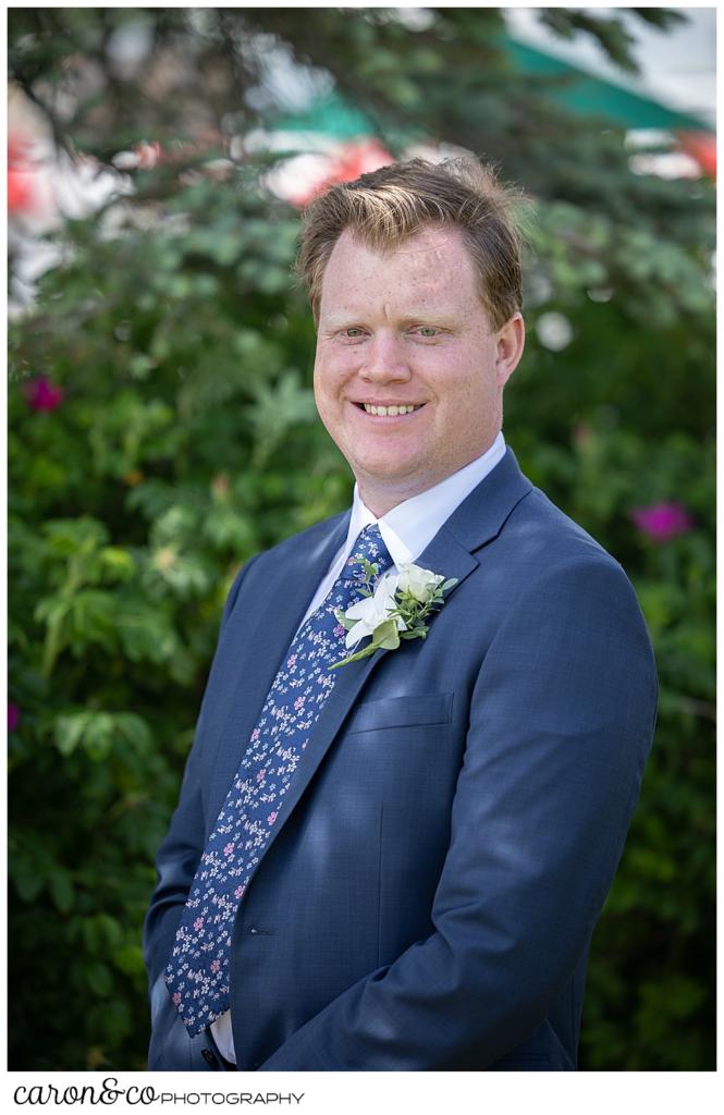a groom wearing a blue suit smiles for the camera