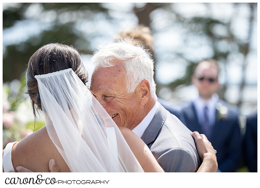 The bride and her dad hug as he escorts the bride toward the officiant