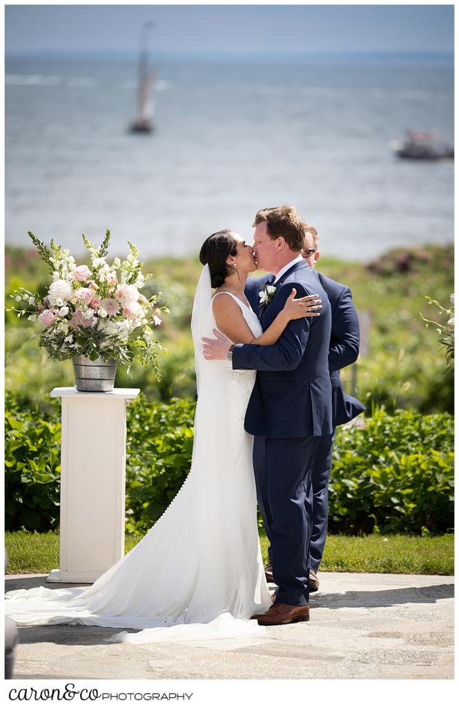 A bride and groom have their first kiss at their Kennebunkport Maine wedding at the colony hotel