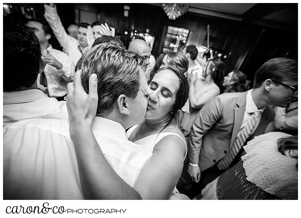 A bride and groom kiss on a crowded dance floor during a Kennebunkport Maine wedding reception at the colony hotel