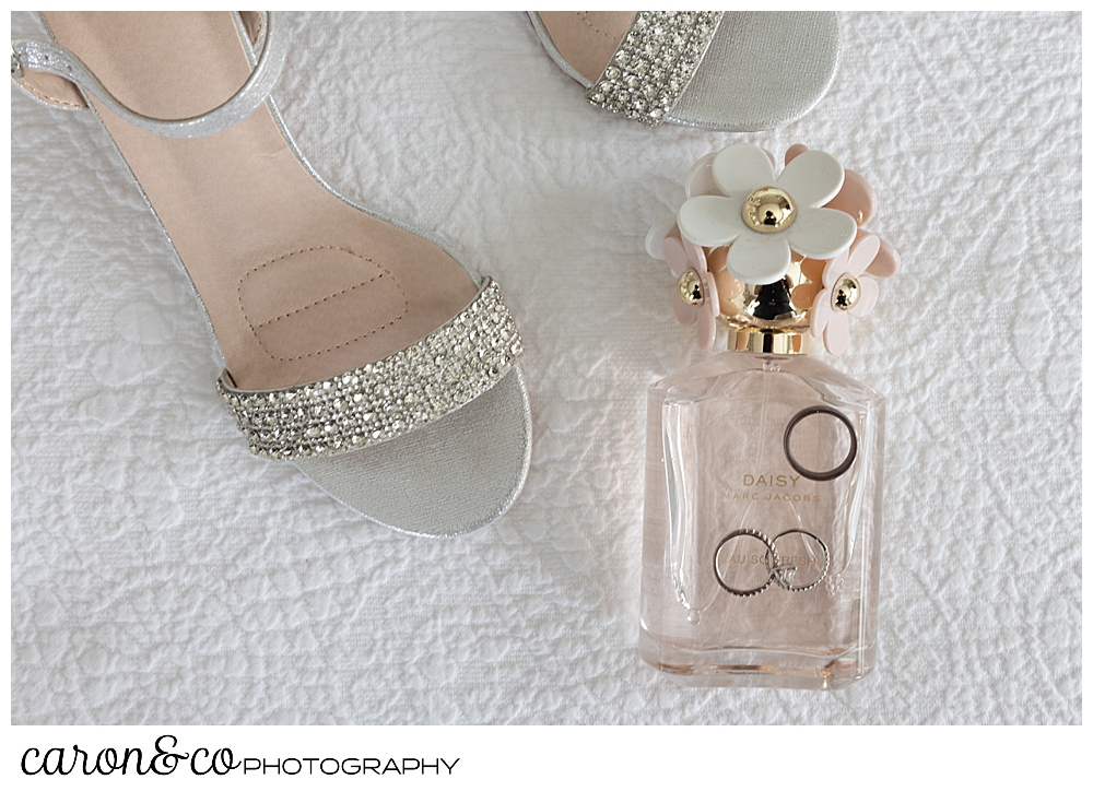 a pair of sparkly shoes, a bottle of Daisy by Marc Jacobs perfume, and wedding rings on a white background