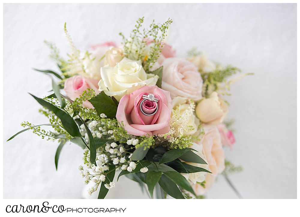 wedding rings sit in a perfect pink rose in a gorgeous white, pink, and green bridal bouquet