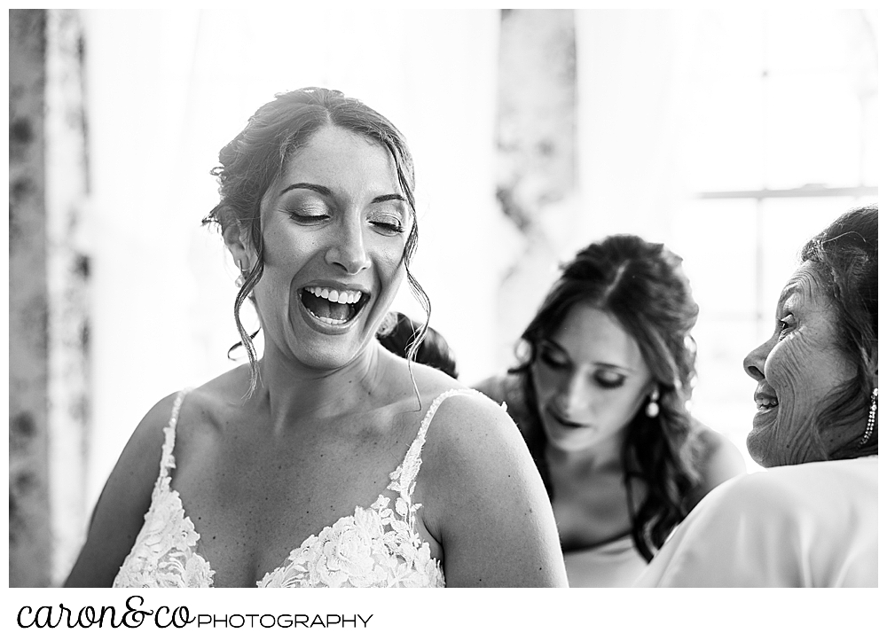 a bride laughs as her bridesmaids button her beautiful wedding dress