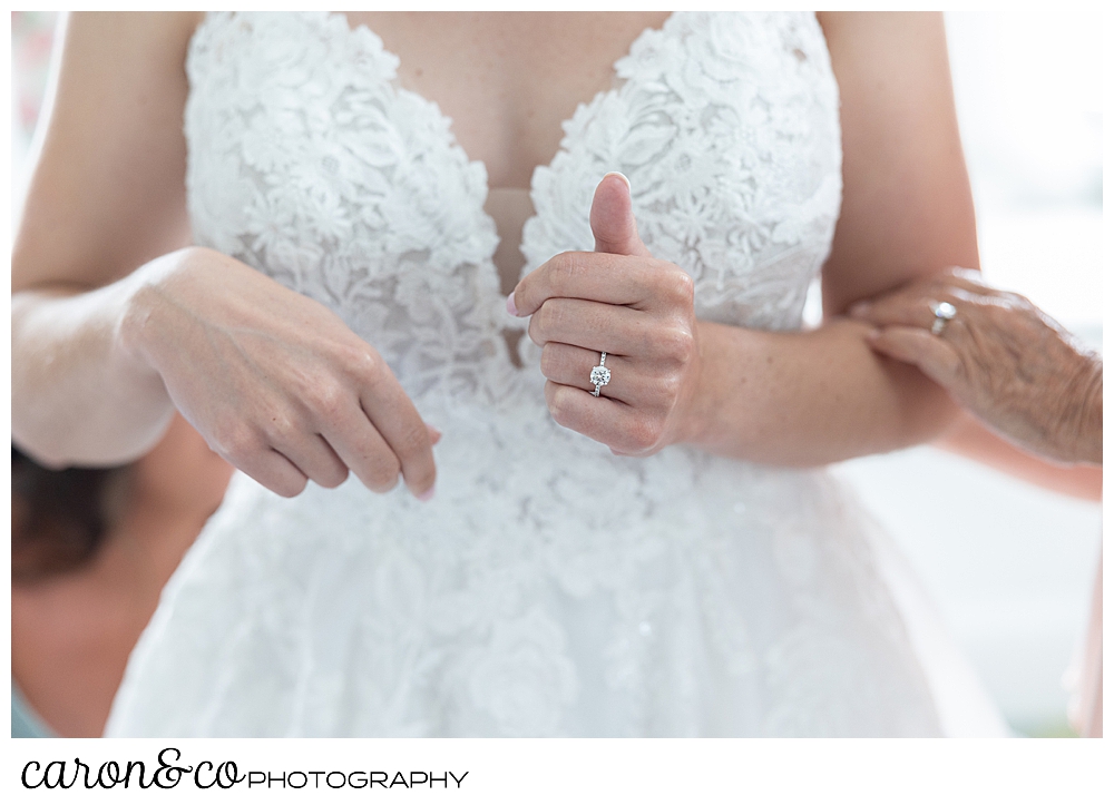 a mother's hand is on the bride's arm as the bride gets into her wedding dress