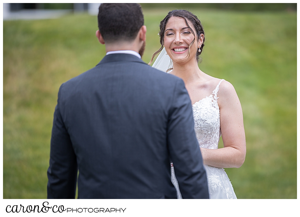 a bride smiles as her groom approaches during a wedding day first look