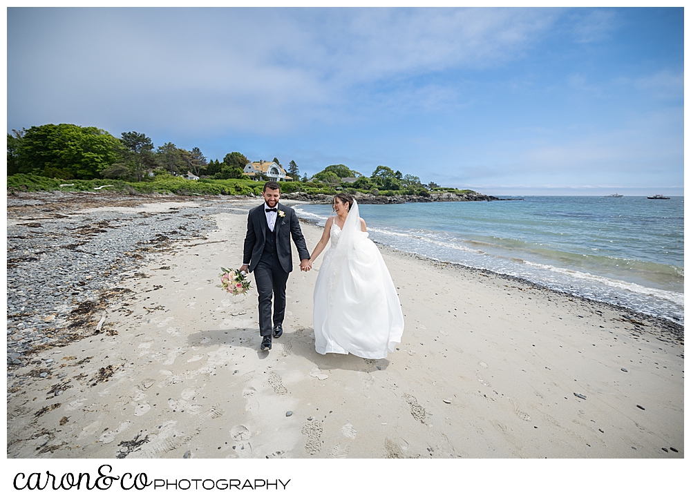 a bride and groom walking hand in hand on Colony Beach, Kennebunkport, Maine
