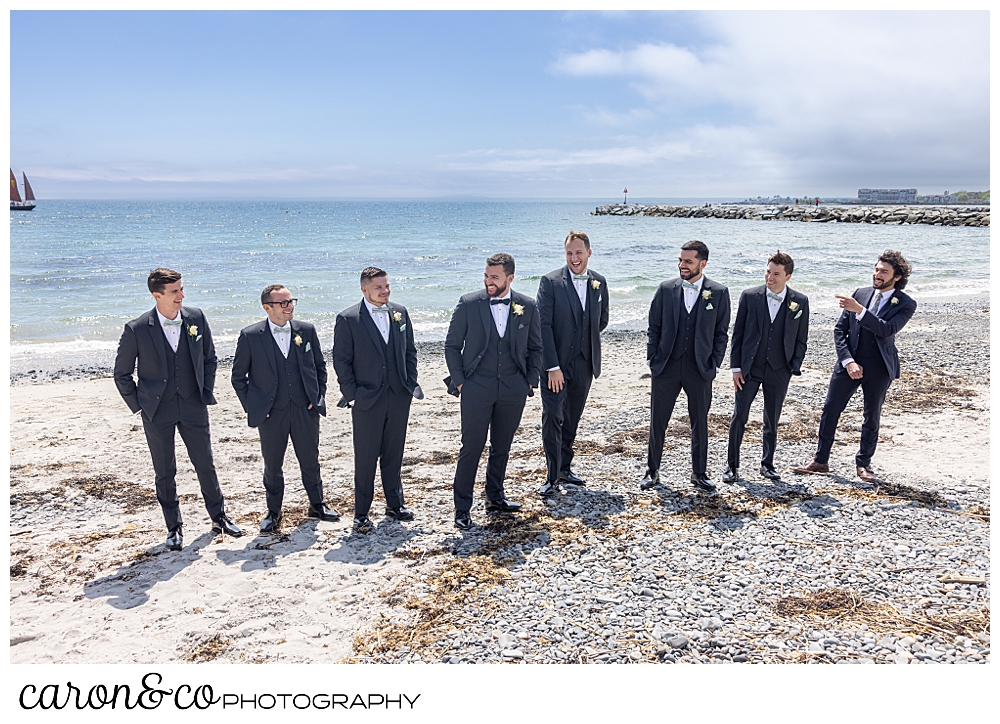 a groom and his groomsmen, dresses in gray suits, stand together on Colony Beach, Kennebunkport Maine