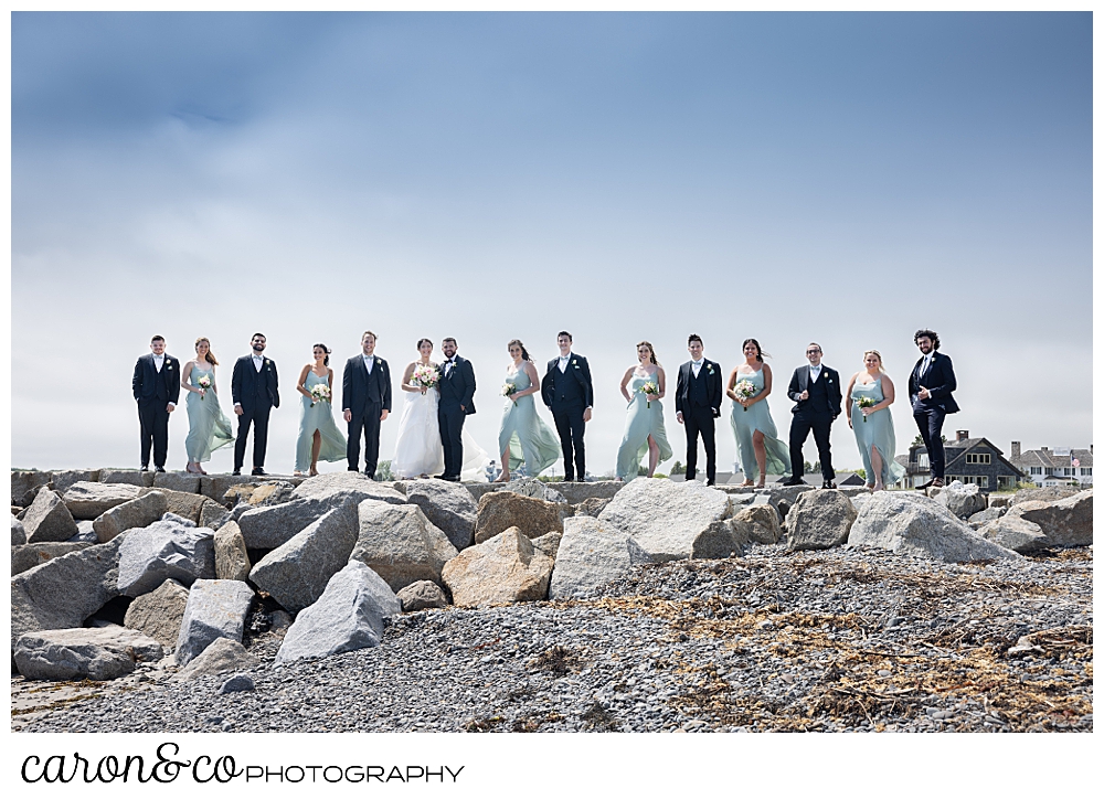 a bride and groom with their bridal party stand on top of the Kennebunkport Maine breakwater