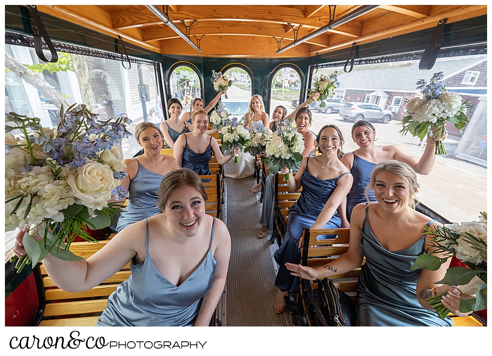 a bride wearing a white dress, and bridesmaids wearing blue, ride the Intown trolley on the way to their maine wedding ceremony