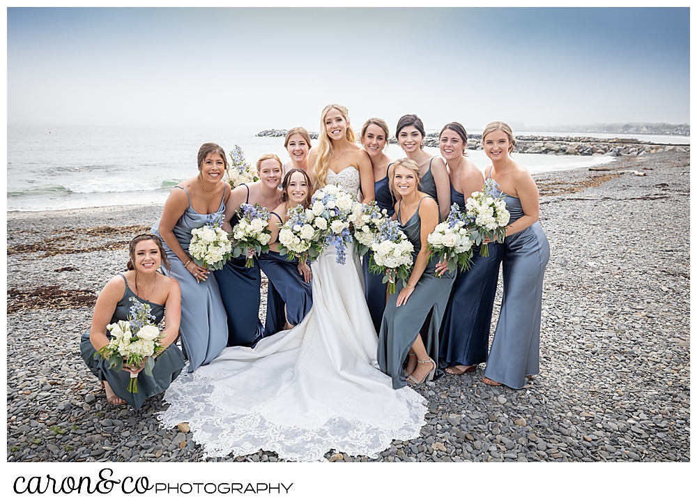 a bride dressed in white, is surrounded by her bridesmaids, dressed in blue, at Colony Beach, Kennebunkport, Maine