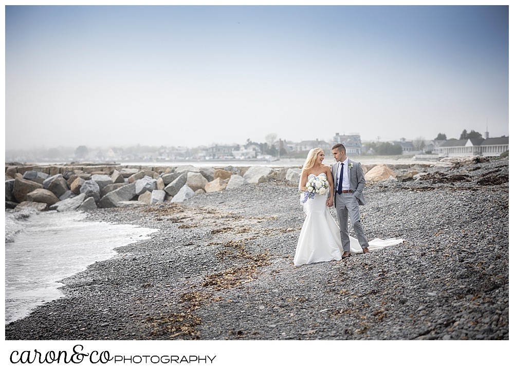 a bride and groom walk along Colony Beach in Kennebunkport, Maine